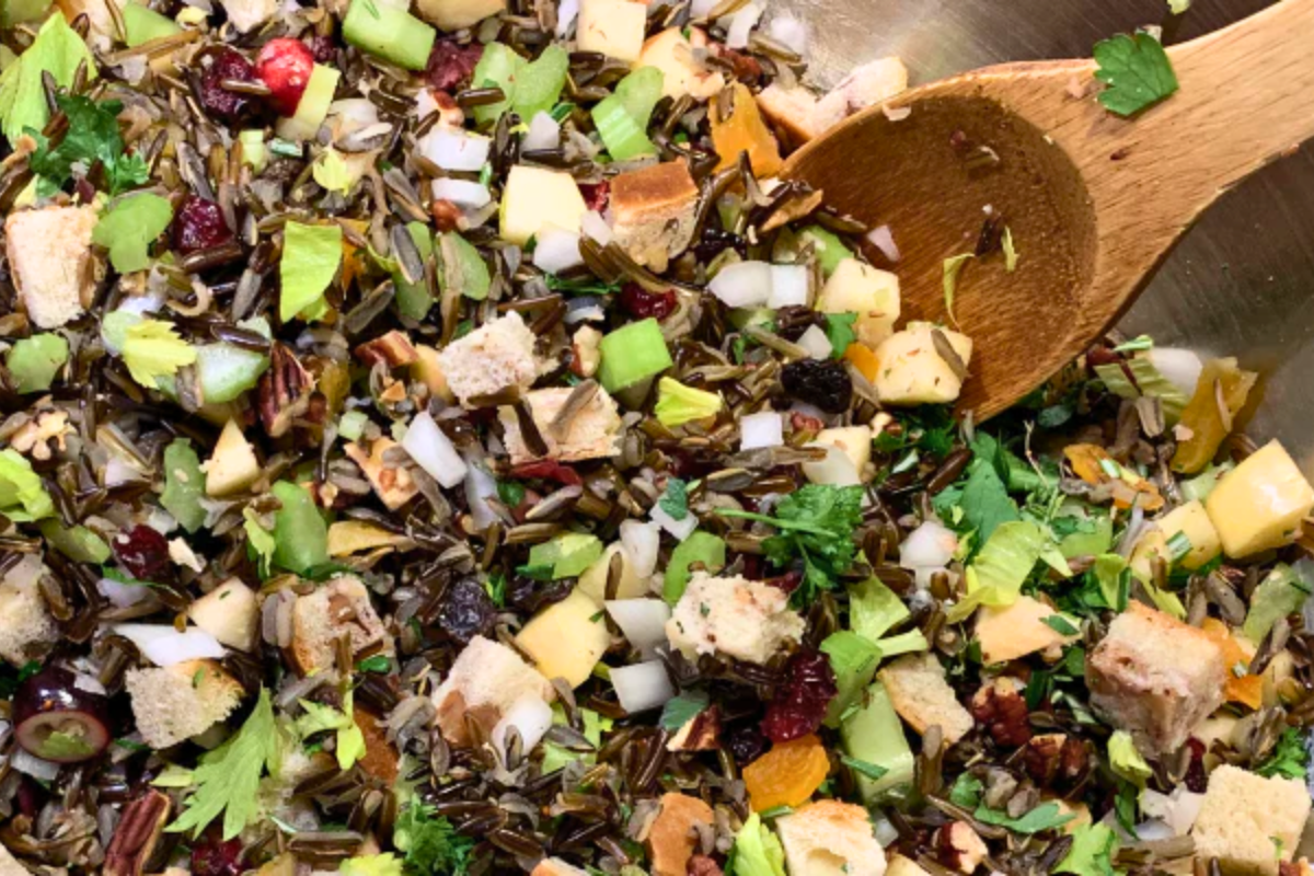 Colorful mix of dried herbs and spices in a pan with a wooden spoon.